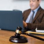 A focused lawyer working on a laptop with a gavel on the desk, indicating legal proceedings.